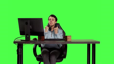 Young-adult-playing-video-games-on-computer-at-desk-against-greenscreen